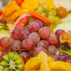 A variety of fresh fruits including grapes, kiwis, and passionfruit in a vibrant, healthy display.