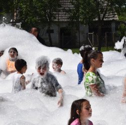 Children having fun in a foam party outdoors during summer.