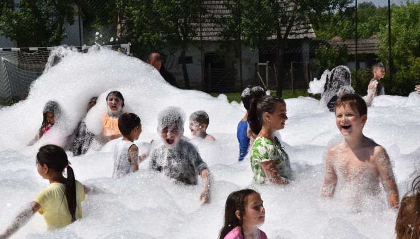Children having fun in a foam party outdoors during summer.